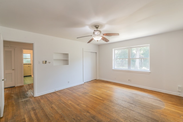 unfurnished bedroom with wood-type flooring, multiple windows, and ceiling fan