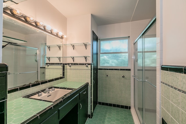 bathroom with a shower with door, tile patterned floors, vanity, and tile walls