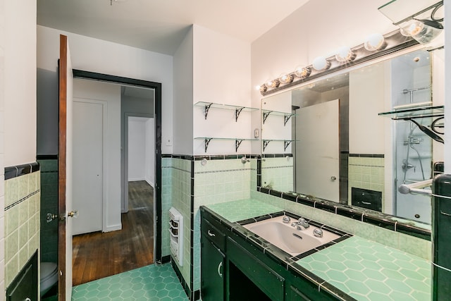 bathroom featuring tile walls, hardwood / wood-style flooring, vanity, and toilet