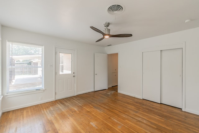 unfurnished bedroom with ceiling fan, two closets, and hardwood / wood-style floors