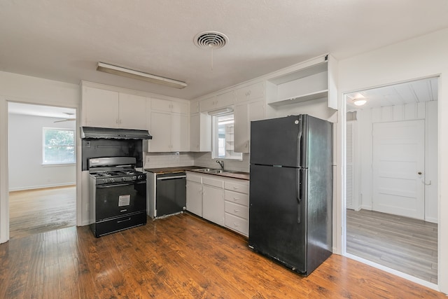 kitchen featuring dark wood-type flooring, black appliances, plenty of natural light, and white cabinetry