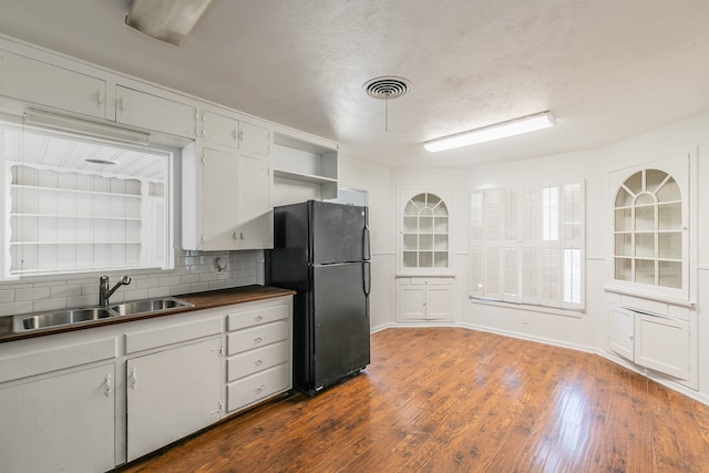 kitchen with black fridge, white cabinets, sink, tasteful backsplash, and dark hardwood / wood-style floors