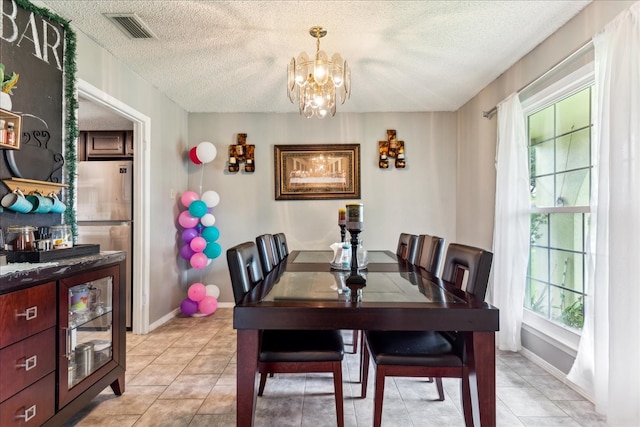 tiled dining area with a textured ceiling and a chandelier