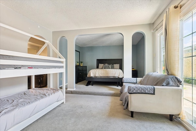 bedroom with multiple windows, carpet flooring, and a textured ceiling