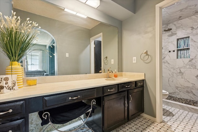 bathroom with tile patterned flooring, a tile shower, vanity, and toilet