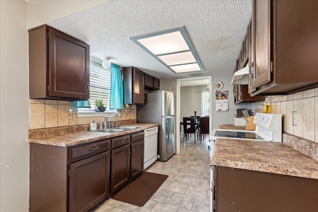 kitchen with dark brown cabinets, white appliances, a textured ceiling, light tile patterned floors, and wall chimney range hood