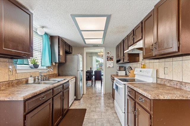 kitchen featuring a wealth of natural light, a textured ceiling, sink, and white appliances