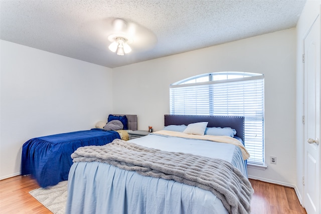 bedroom with hardwood / wood-style floors, a textured ceiling, and ceiling fan