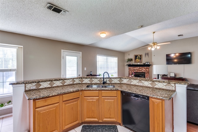 kitchen with black dishwasher, a wealth of natural light, sink, and a brick fireplace