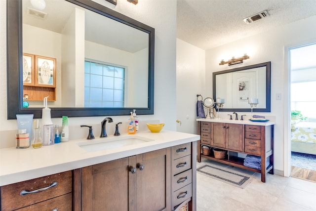 bathroom featuring a textured ceiling, dual bowl vanity, and tile patterned floors