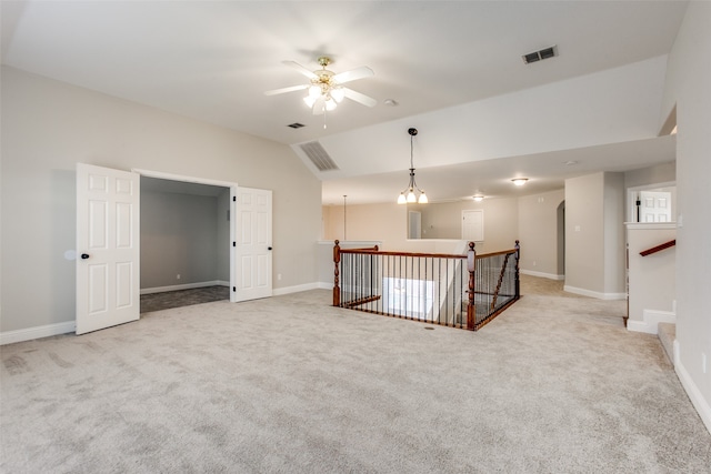 unfurnished room featuring ceiling fan with notable chandelier, vaulted ceiling, and light carpet