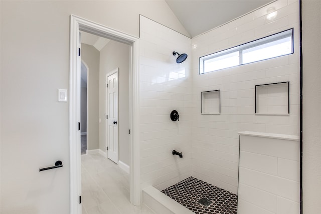 bathroom featuring tile patterned flooring, tiled shower, and lofted ceiling