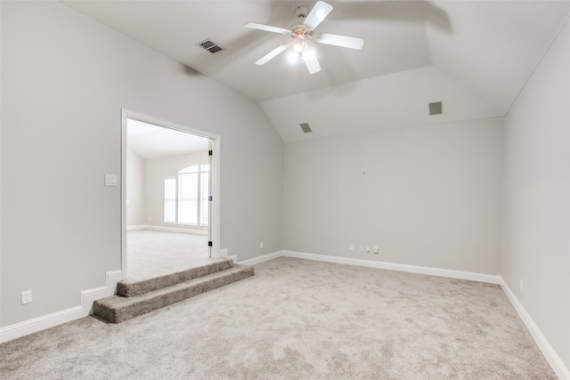 empty room featuring ceiling fan, vaulted ceiling, and light colored carpet