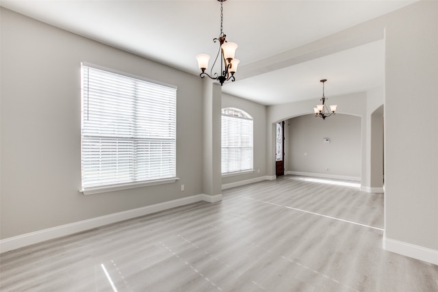 unfurnished room with hardwood / wood-style flooring, an inviting chandelier, and a healthy amount of sunlight