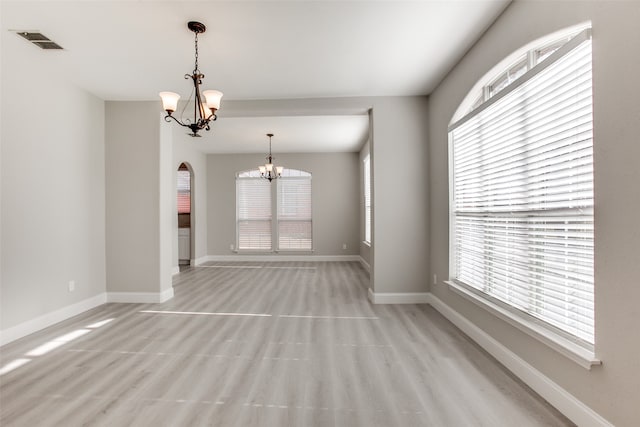 unfurnished living room featuring light hardwood / wood-style flooring and a chandelier