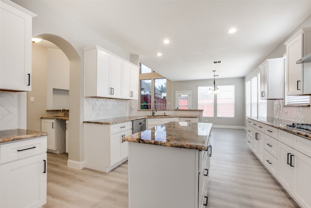 kitchen with sink, light hardwood / wood-style flooring, stone countertops, tasteful backsplash, and a kitchen island