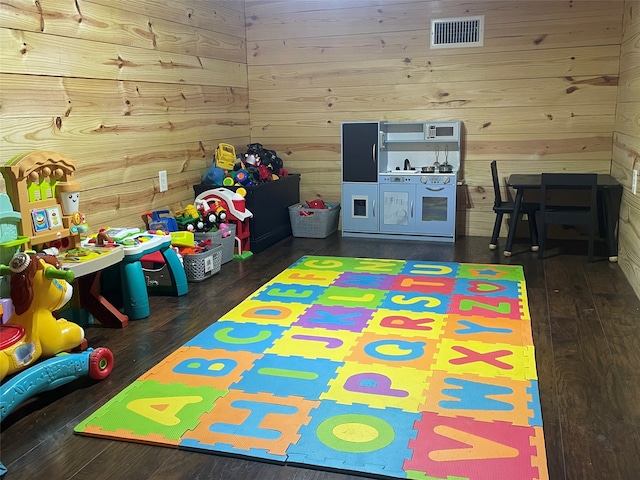 recreation room featuring wooden walls and dark hardwood / wood-style floors