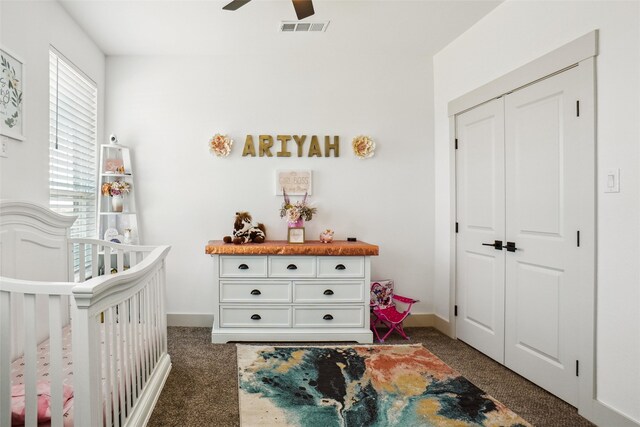 carpeted bedroom featuring ceiling fan, a crib, and a closet