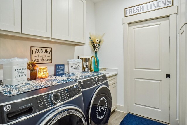 laundry room featuring washer and clothes dryer, cabinets, and light wood-type flooring