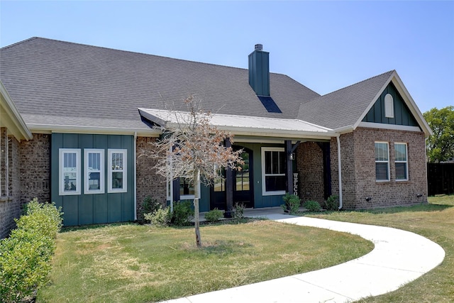 view of front of home with brick siding, board and batten siding, a chimney, and a front lawn