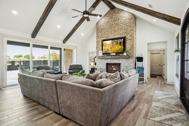 living room with beamed ceiling, ceiling fan with notable chandelier, high vaulted ceiling, and light hardwood / wood-style flooring