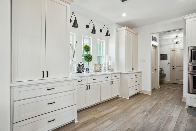 kitchen with white cabinetry, light hardwood / wood-style flooring, and stainless steel appliances