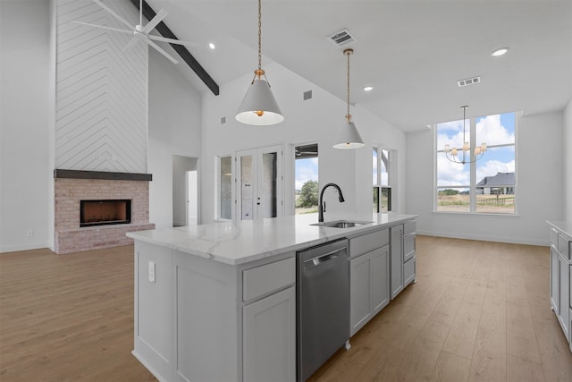 kitchen with sink, stainless steel dishwasher, light hardwood / wood-style flooring, and an island with sink