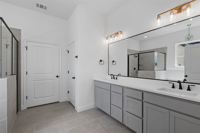 bathroom with a shower with door, double vanity, and tile patterned floors