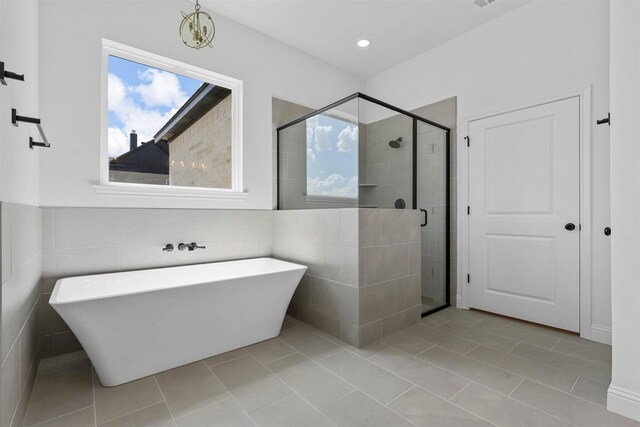 bathroom with tile walls, separate shower and tub, and tile patterned floors