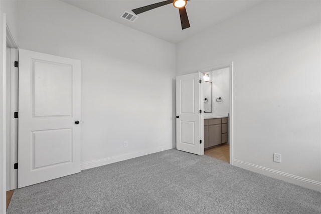 unfurnished bedroom with ceiling fan, ensuite bathroom, and light carpet