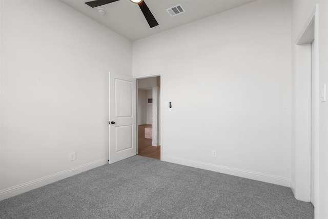 unfurnished room featuring carpet, a towering ceiling, and ceiling fan