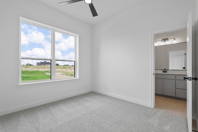 unfurnished bedroom featuring ensuite bath, light colored carpet, and multiple windows