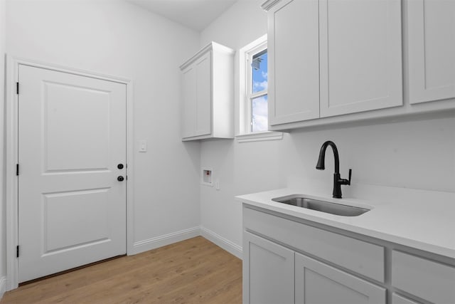 laundry area featuring light hardwood / wood-style floors, sink, hookup for a washing machine, and cabinets