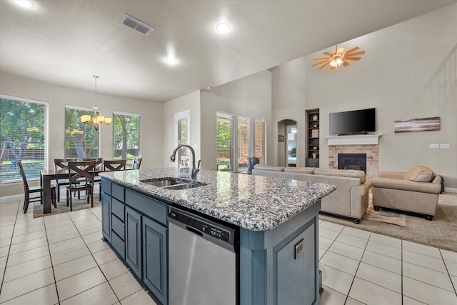 kitchen featuring visible vents, stainless steel dishwasher, light tile patterned flooring, a glass covered fireplace, and a sink