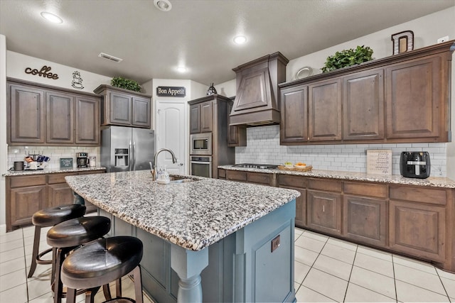kitchen featuring custom exhaust hood, stainless steel appliances, light tile patterned floors, a sink, and visible vents