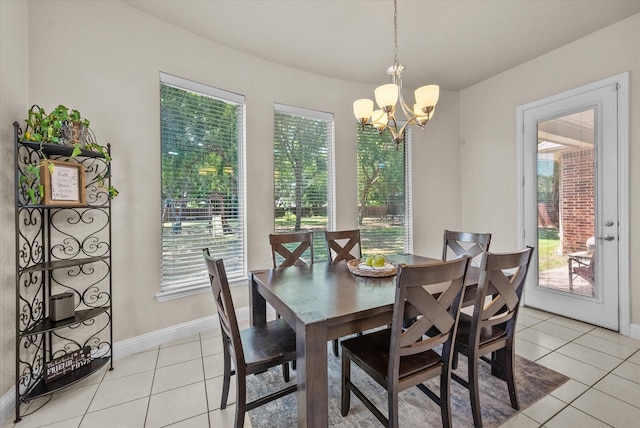 dining area featuring light tile patterned flooring, a notable chandelier, and baseboards