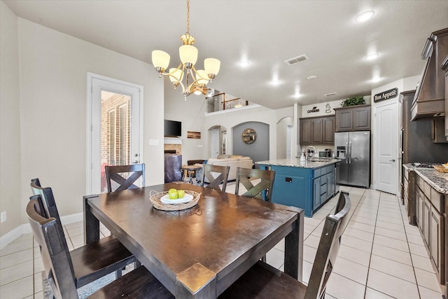 dining space featuring light tile patterned flooring, visible vents, arched walkways, and a chandelier