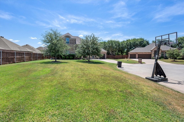 view of yard with driveway, an attached garage, and fence