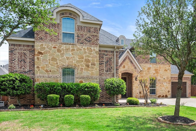 view of front facade featuring concrete driveway, stone siding, a front yard, an attached garage, and brick siding