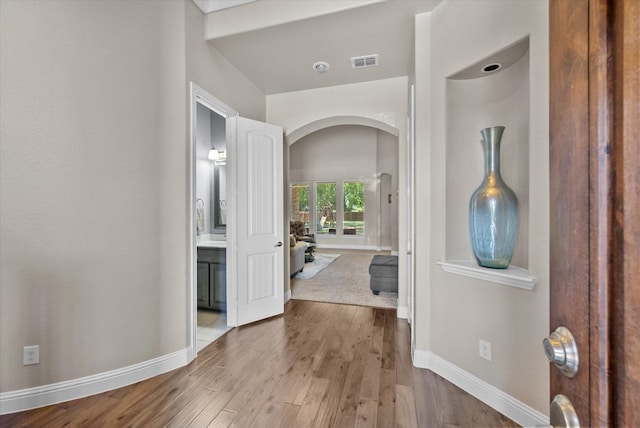 entryway with arched walkways, visible vents, wood finished floors, and baseboards
