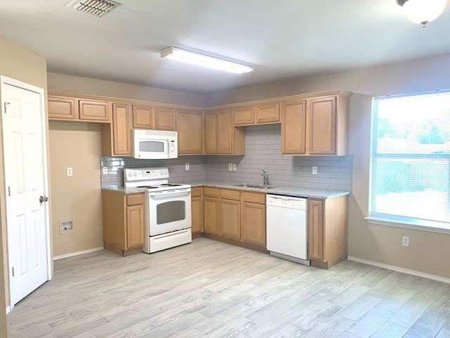 kitchen featuring light stone countertops, sink, tasteful backsplash, white appliances, and light wood-type flooring