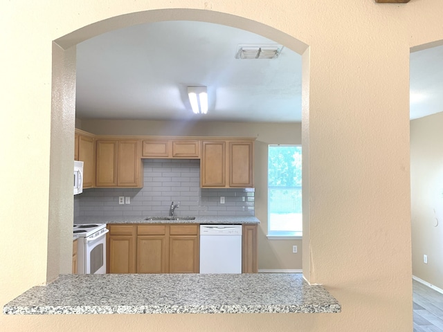 kitchen with backsplash, sink, hardwood / wood-style floors, and white appliances