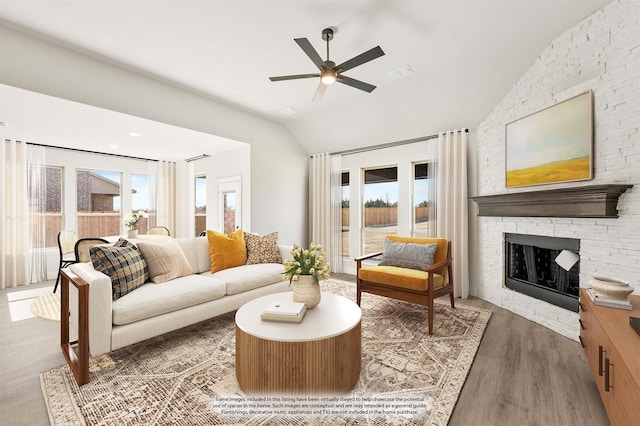 living area with lofted ceiling, ceiling fan, a fireplace, wood finished floors, and visible vents