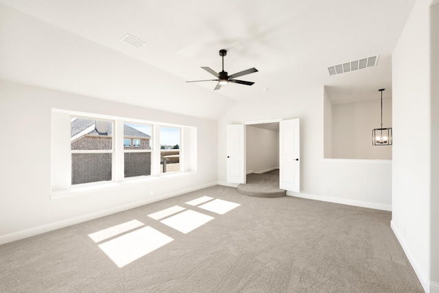 interior space featuring vaulted ceiling, carpet flooring, and ceiling fan with notable chandelier