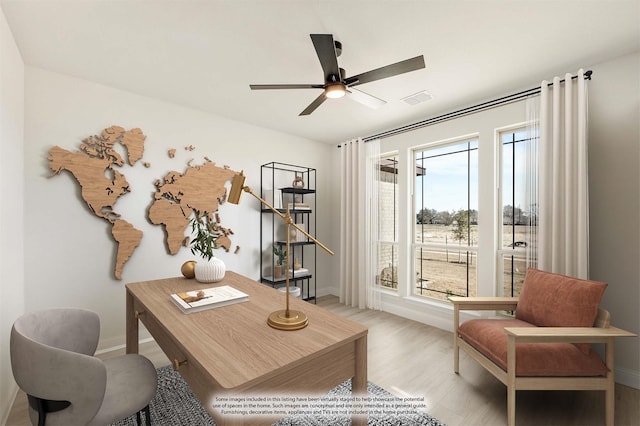 home office featuring light wood finished floors, ceiling fan, visible vents, and baseboards