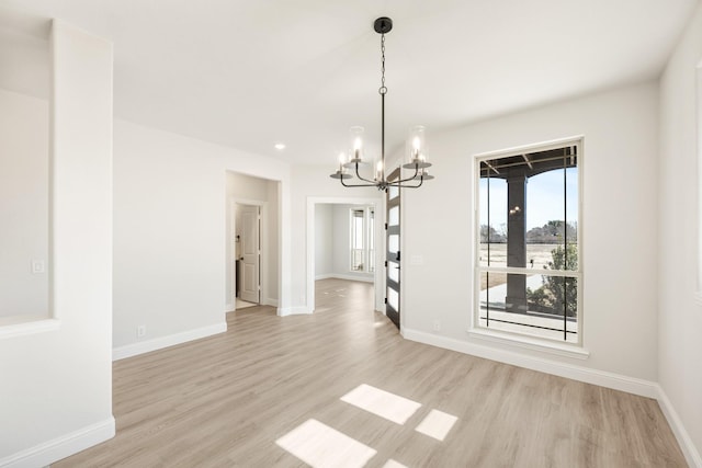 unfurnished dining area featuring an inviting chandelier and light wood-type flooring