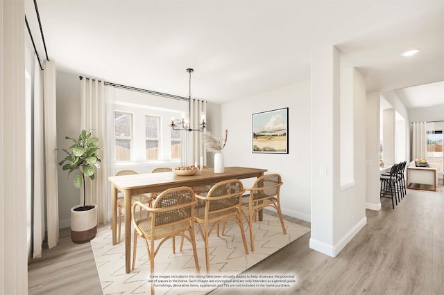 dining area featuring baseboards, an inviting chandelier, and light wood-style floors