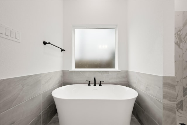 bathroom with a bathtub and tile walls