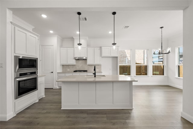 kitchen with sink, stainless steel appliances, pendant lighting, a center island with sink, and white cabinets