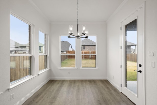 unfurnished dining area with an inviting chandelier, a healthy amount of sunlight, and crown molding